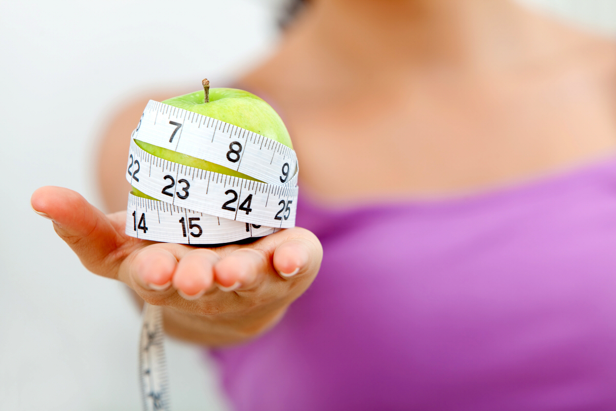 Woman holding an apple with a tape measure